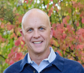 A man with bald head and blue eyes.