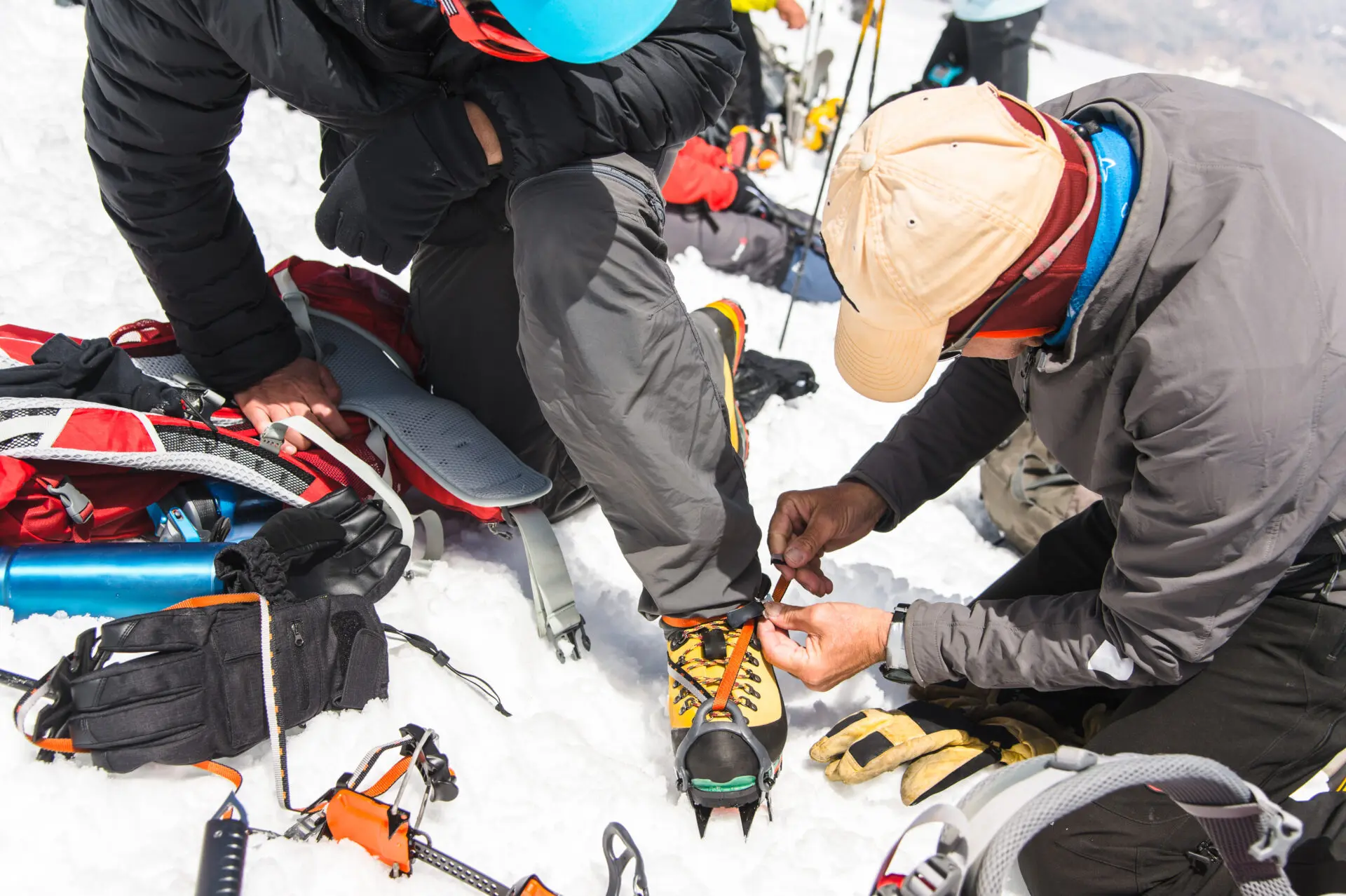 A professional guide helps you set up and dress alpinist crampons for a beginner mountaineer before climbing