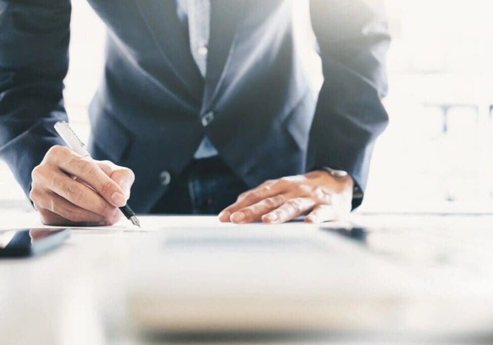A man in a suit is writing on paper