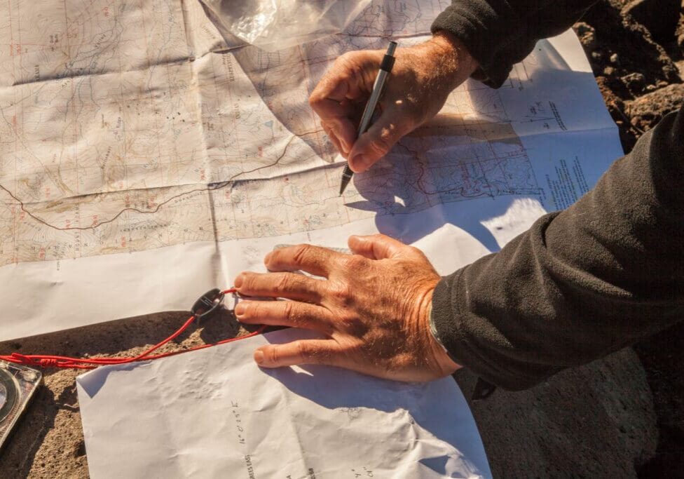 Hands marking topographic map with compass